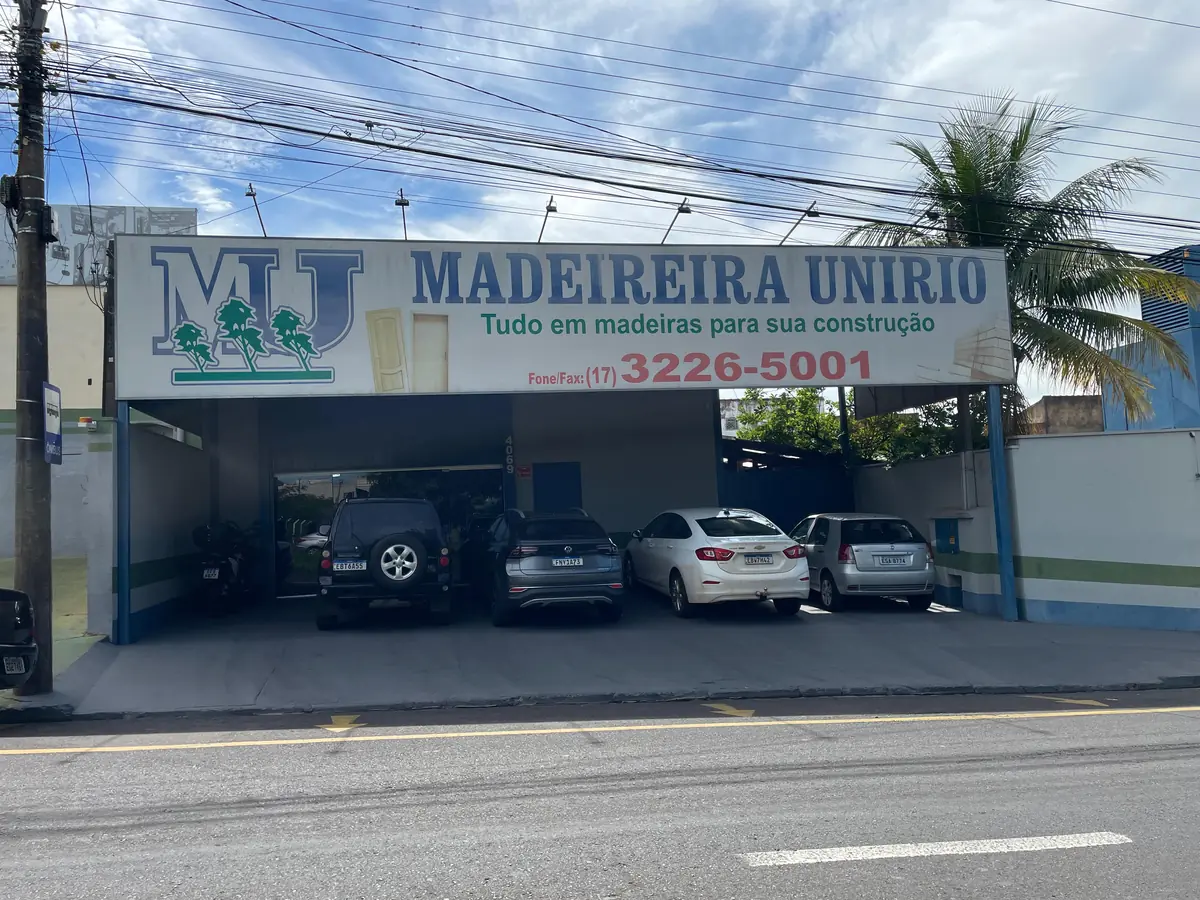Fachada da Madeireira Unirio na Av. Potirendaba: prédio térreo com placa azul e branca da marca sobre a entrada e carros estacionados sob a marquise.