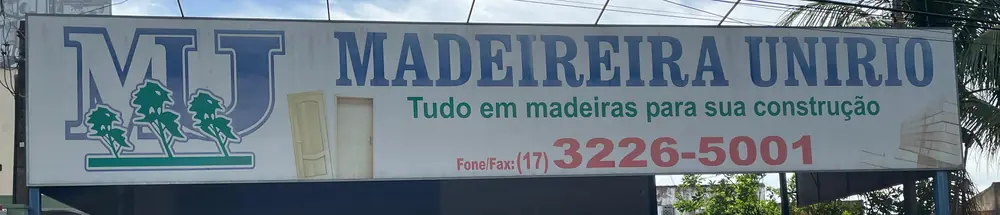 Placa da fachada: o monograma MU com três árvores, o nome MADEIREIRA UNIRIO, a frase "Tudo em madeiras para sua construção" e o telefone (17) 3226-5001.